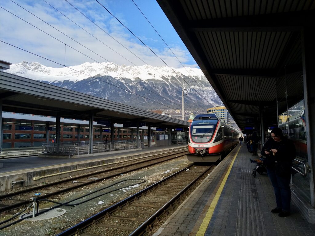 Train at the railway station of Innsbruck with snow-capped mountains in the background, photo by Sophie Huijts