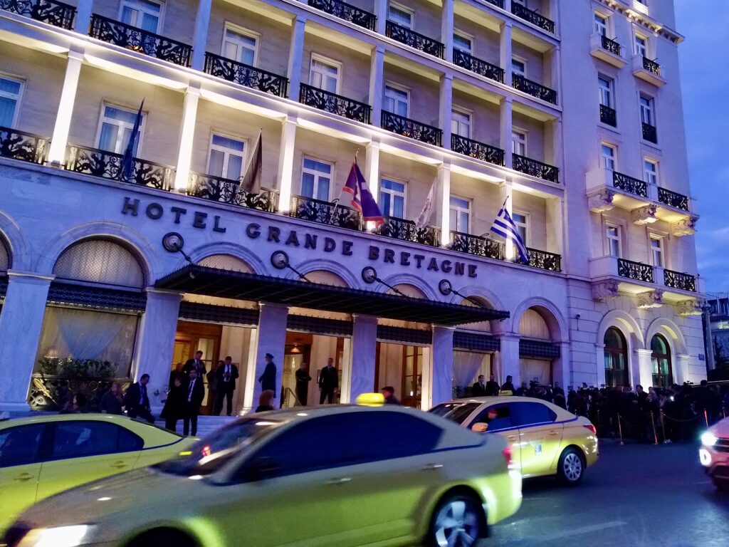 Entrance of Hotel Grande Bretagne with press and yellow taxis at Syntagma Square in Athens, photo by Sophie Huijts