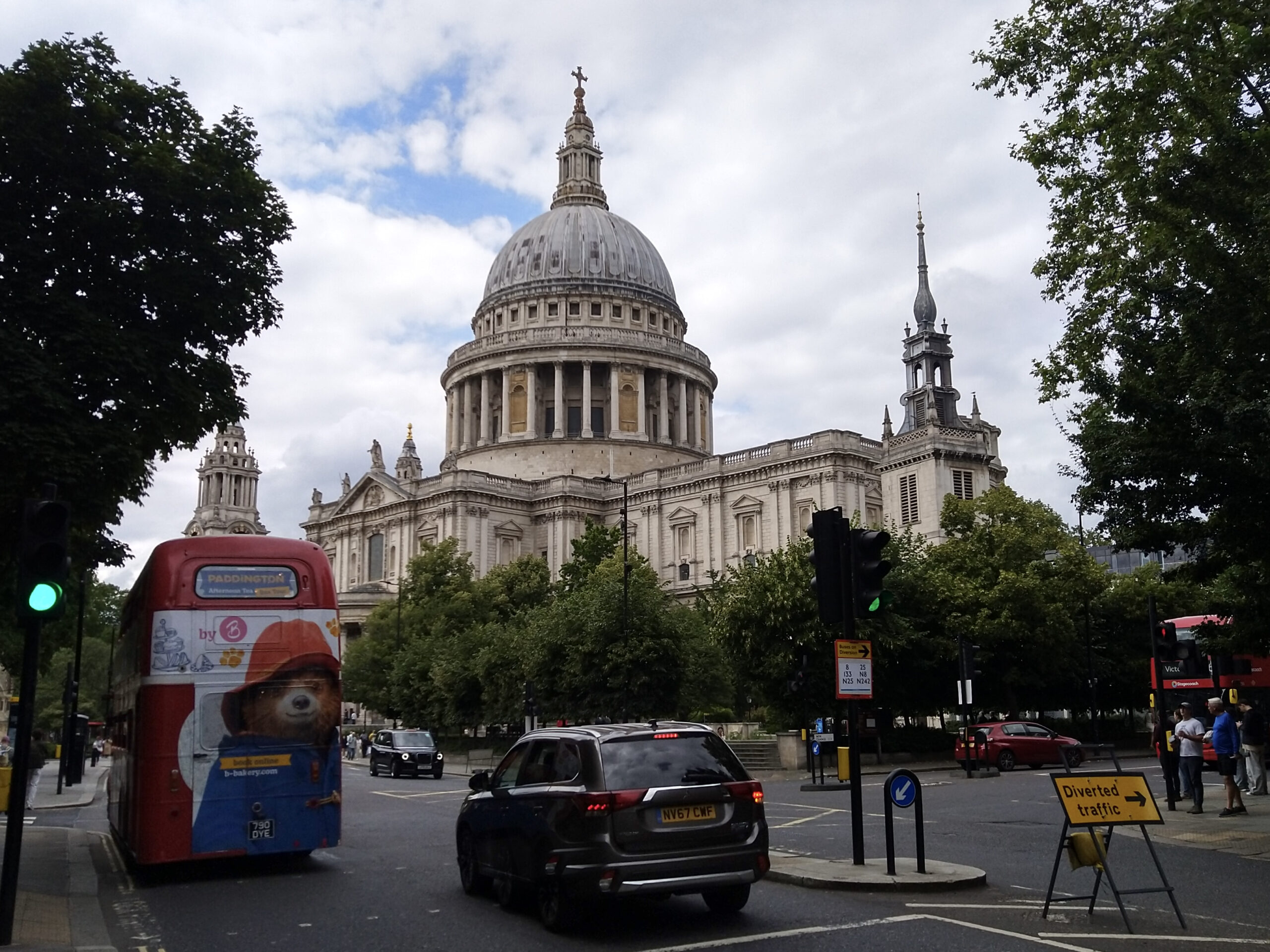 St Paul's Cathedral in London with traffic in front including a red double-decker bus with a print of Paddington Bear and a black taxi cab, photo by Sophie Huijts