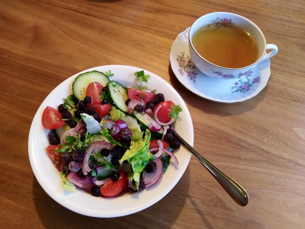 Salad with lettuce, tomato, cucumber, red onion, wild blueberries and parsley with a cup of tea, prepared and photo by Sophie Huijts